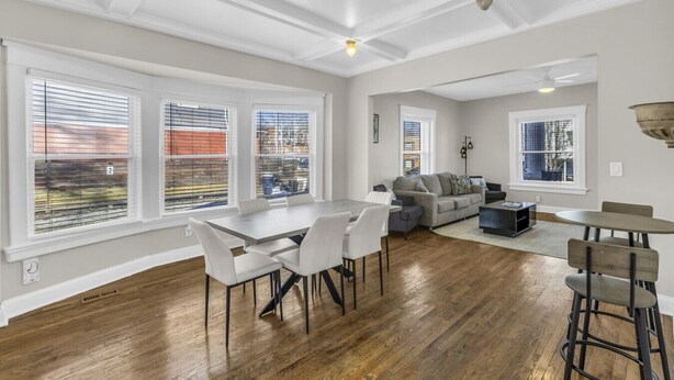 A spacious living room with a dining area, large windows, and a modern ceiling design.