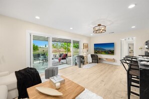 Relax in this stylish living area with a sliding glass door leading to an outdoor patio, featuring a sofa, chairs, and dining table.