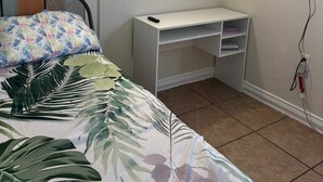 A bedroom with a bed, a desk, a TV, and wall art. - Neverland. (Jacksonville)