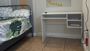 A bedroom with a bed, a desk, and a TV mounted on the wall. - Neverland. (Jacksonville)