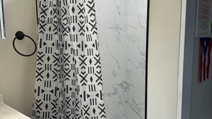 A bathroom with a shower curtain featuring a geometric pattern, a white sink, and a marble wall. - Neverland. (Jacksonville)