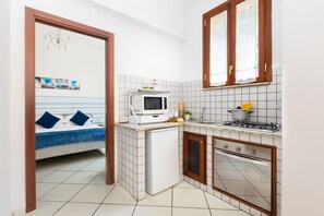 A compact kitchen with a microwave, stove, and small refrigerator.