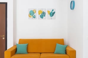 A room with a mustard-colored sofa, teal cushions, and three framed leaf artworks on the wall. - Charming&Modern One-Bedroom Apartment in Sorrento (Sorrento)