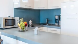 A modern kitchen with white cabinets, a microwave, a coffee maker, and a fruit bowl on the counter. - Awesome apartment in Rogoznica (Rogoznica)