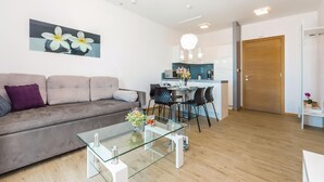 A modern living room with a glass coffee table, a sofa, and a dining area with chairs. - Awesome apartment in Rogoznica (Rogoznica)