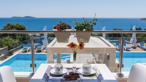 A balcony with a pool view, a table with cups and cookies, and potted plants. - Awesome apartment in Rogoznica (Rogoznica)