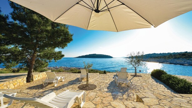 A stone patio with white lounge chairs and an umbrella overlooking a coastal view. - Awesome apartment in Rogoznica (Rogoznica)