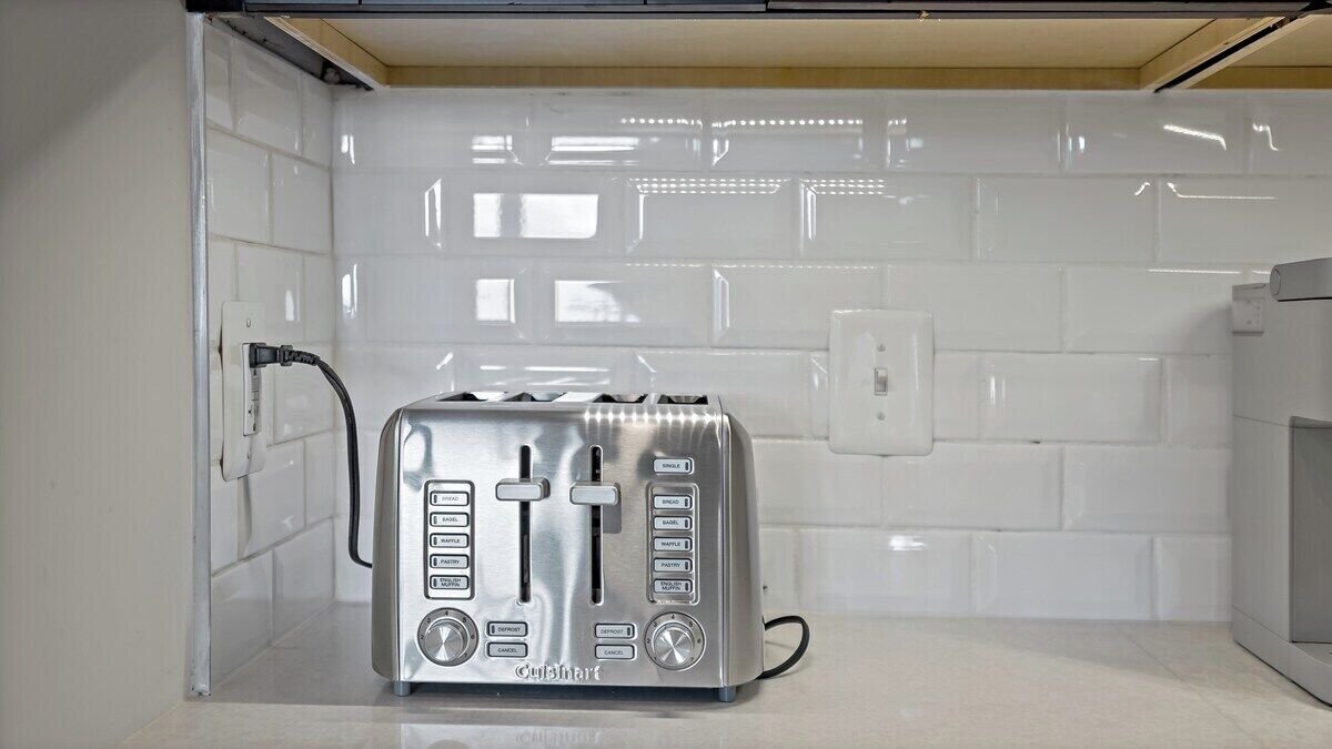 Eine Küche mit weißen Fliesen, einem eingebauten Toaster und einer Arbeitsplatte.
