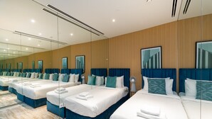 A hotel room with three beds, each with blue headboards and white bedding.