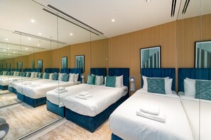 A hotel room with three beds, each with blue headboards and white bedding.