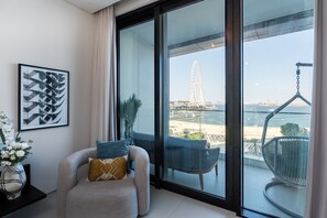 A modern living room with a large window overlooking a beach and a Ferris wheel.
