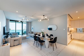 Una sala de estar moderna con comedor, un ventanal grande y una cocina.