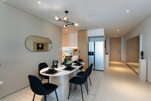 Een moderne keuken met witte kasten, een centraal kookeiland met zitplaatsen en een kroonluchter.