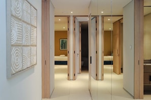 Een moderne hotelkamer met een groot bed, een nachtkastje en een spiegel. Er is een houten deur die naar een andere kamer leidt.