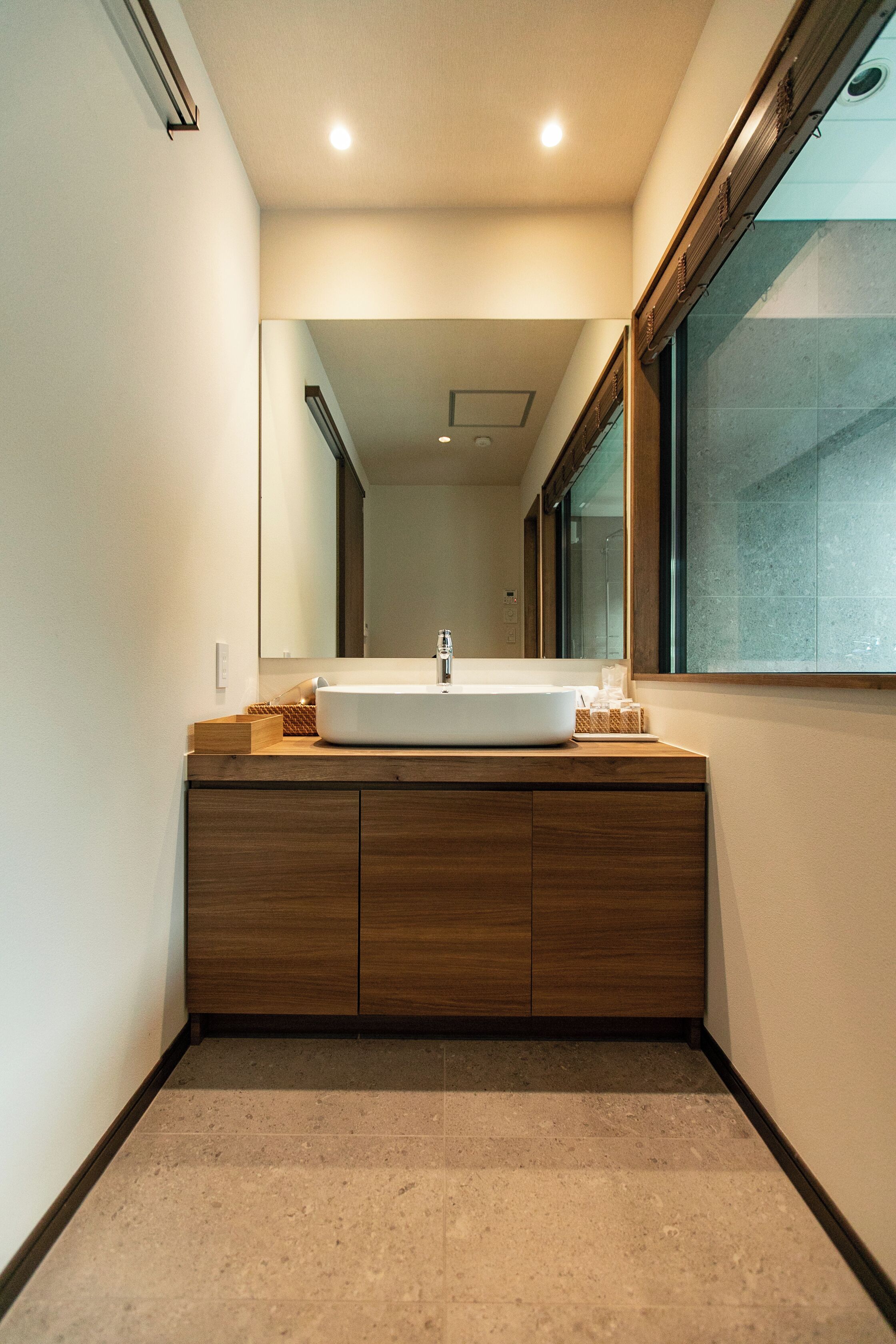 A modern bathroom with a large mirror, a wooden vanity, and a white sink.