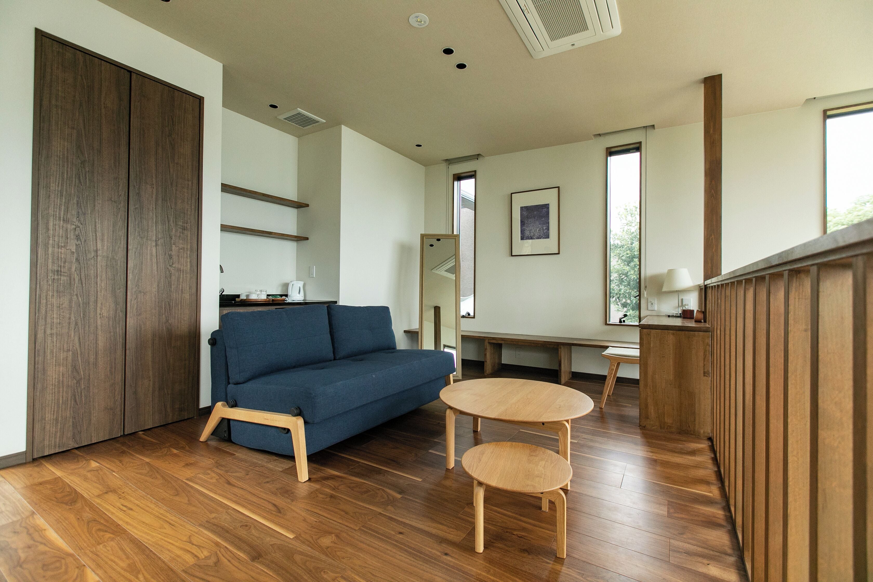 A modern living room with a sofa, two wooden tables, and a wooden cabinet.