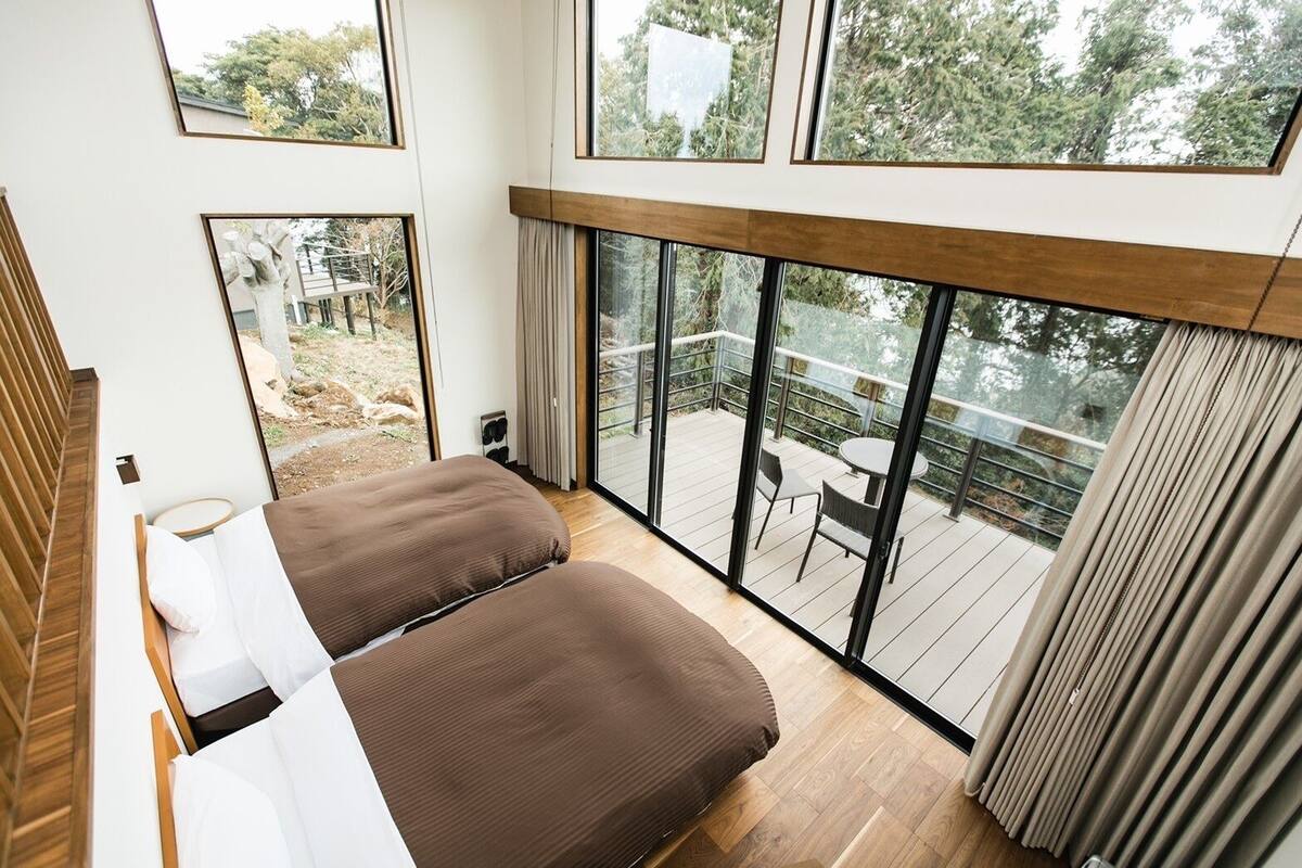 Une chambre avec une grande fenêtre donnant sur une terrasse.