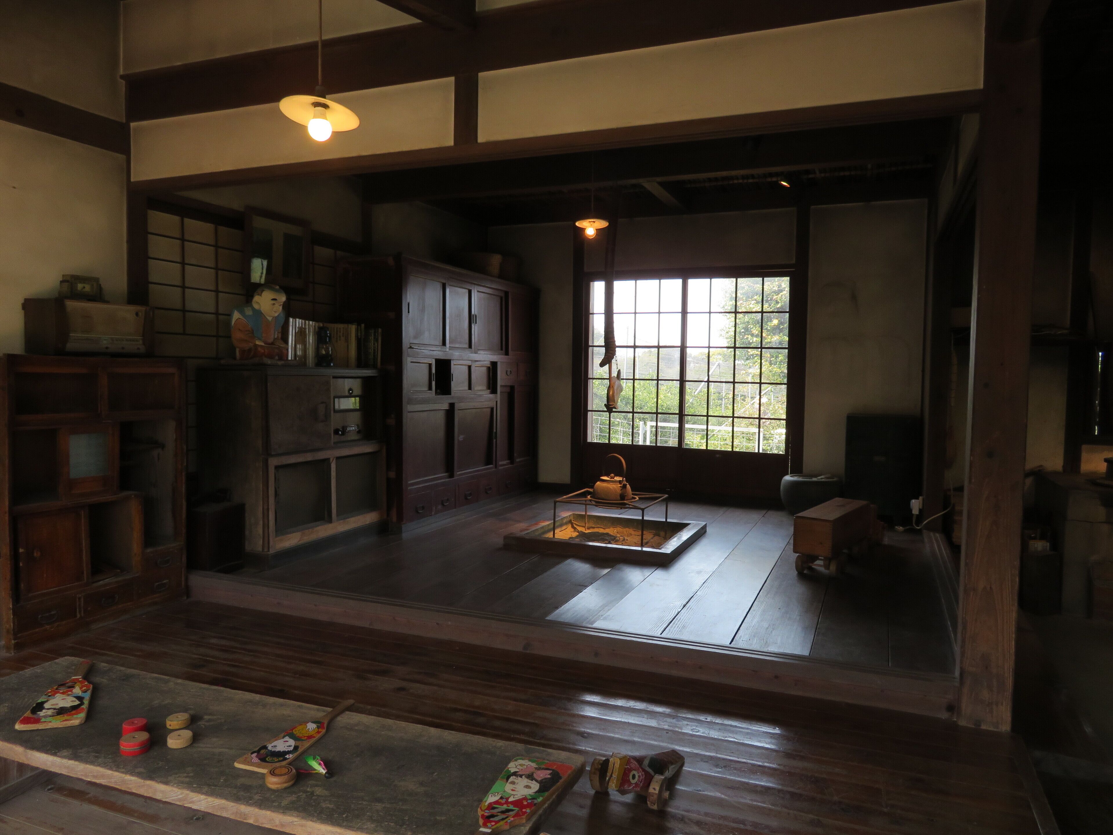 A traditional Japanese room with tatami flooring, wooden furniture, and a large window providing natural light.