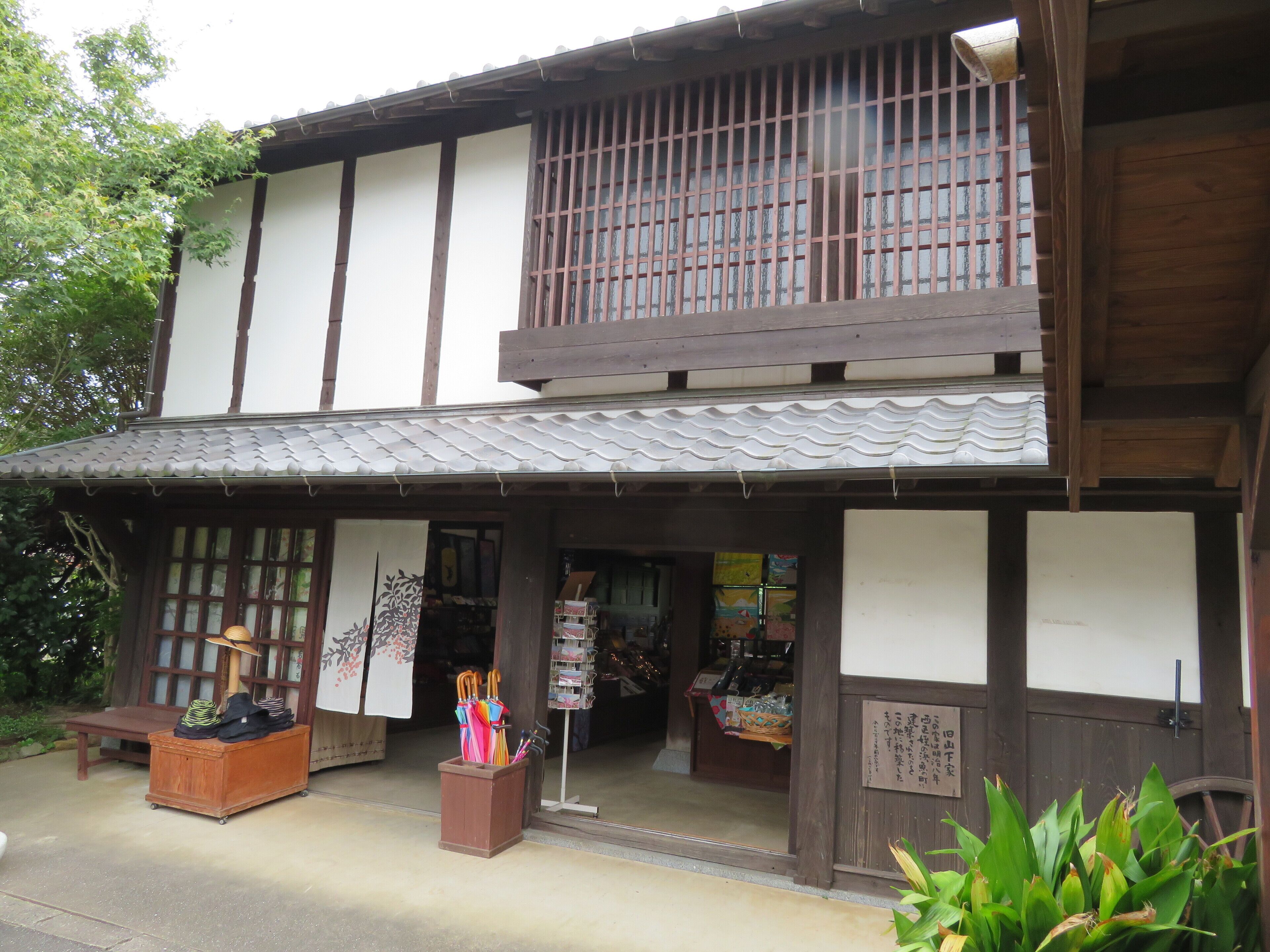 Un edificio tradicional japonés con fachada de madera, techo de tejas y una pequeña entrada a una tienda.