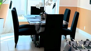 Zona pranzo con tavolo e sedie, un lampadario e vista attraverso un'ampia finestra.