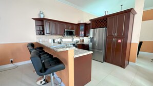 Una cucina moderna con mobili marrone scuro, elettrodomestici in acciaio inossidabile e un'isola centrale con sgabelli da bar.