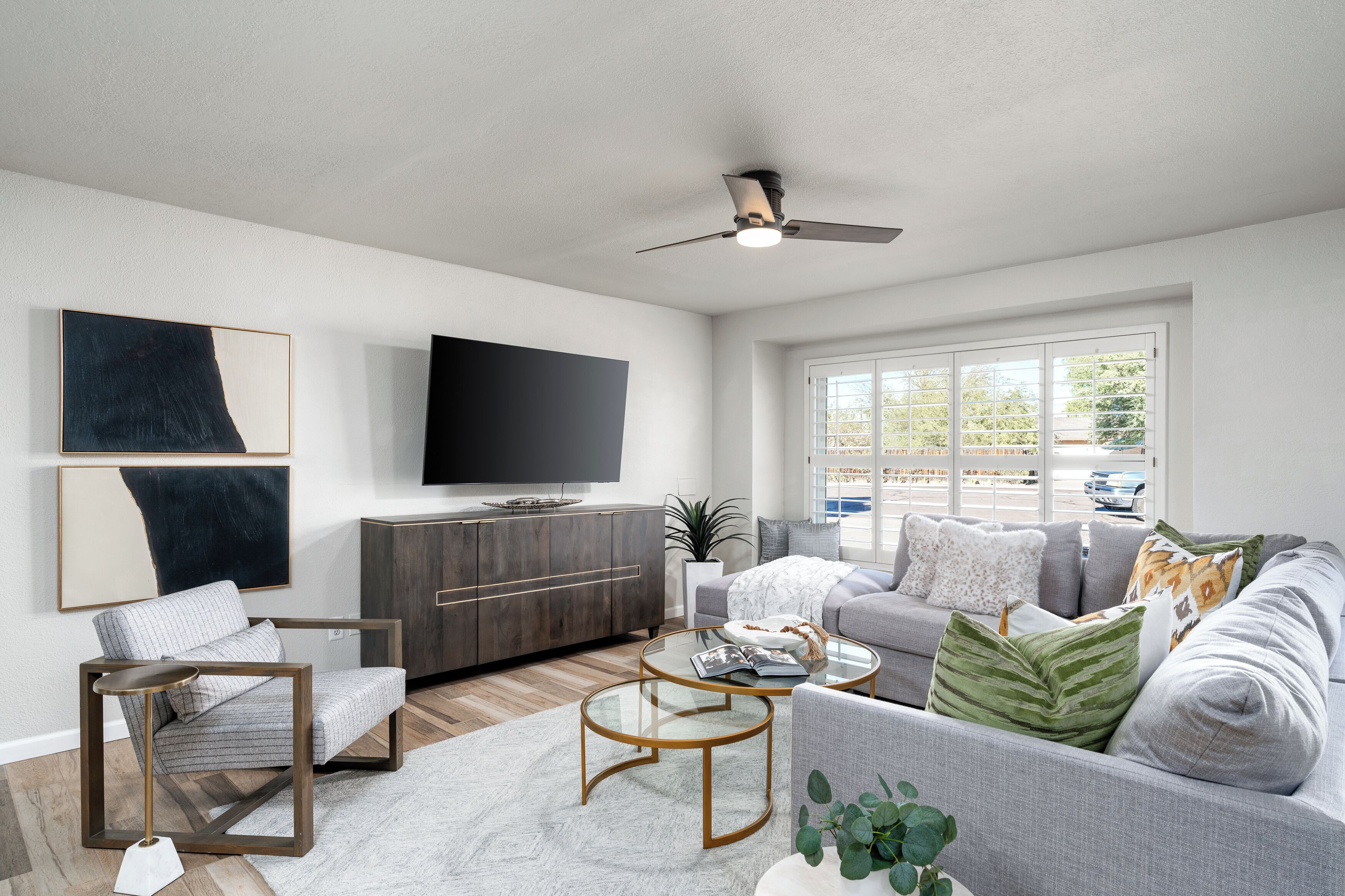 A modern living room with a flat-screen TV, a grey sofa, a coffee table, and a chair.