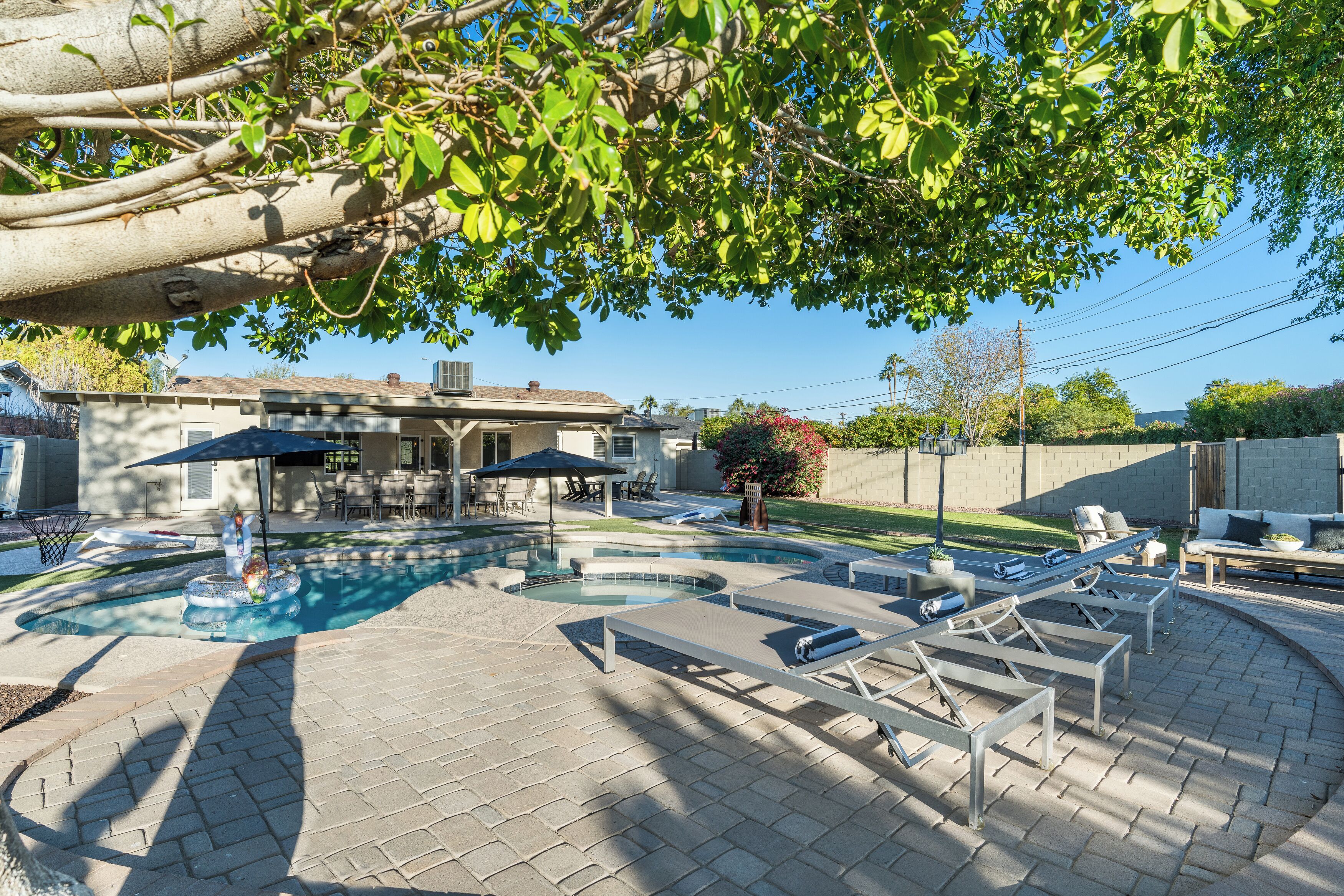 A backyard with a swimming pool, lounge chairs, and a patio area.