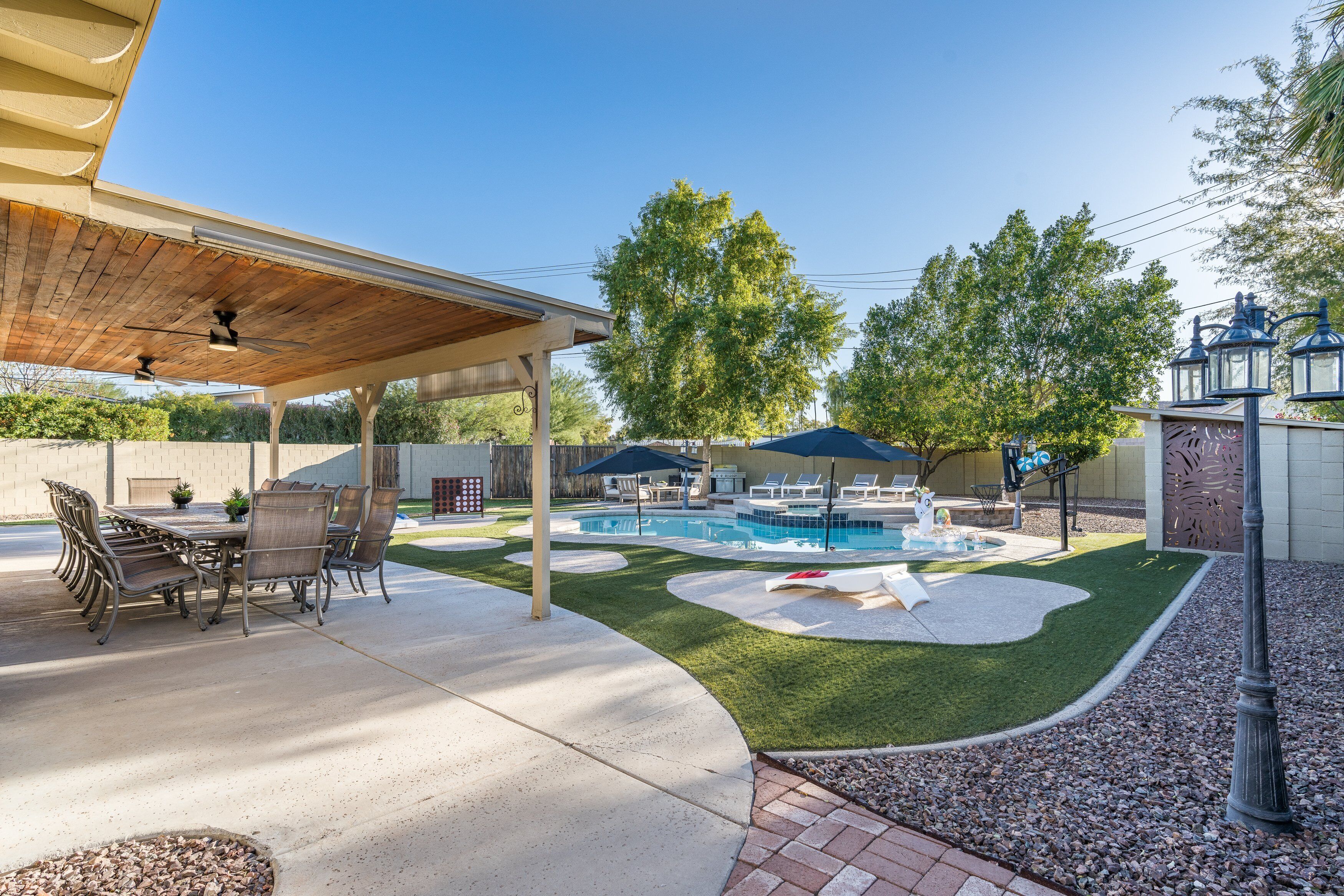 Eine überdachte Terrasse mit Pool, Liegestühlen und Essbereich.