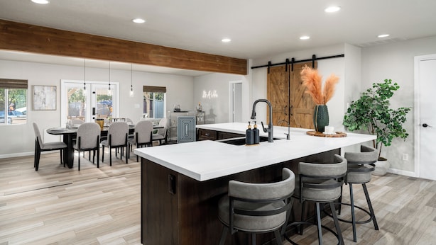 A modern kitchen with a large island, bar stools, and a dining area with a table and chairs.