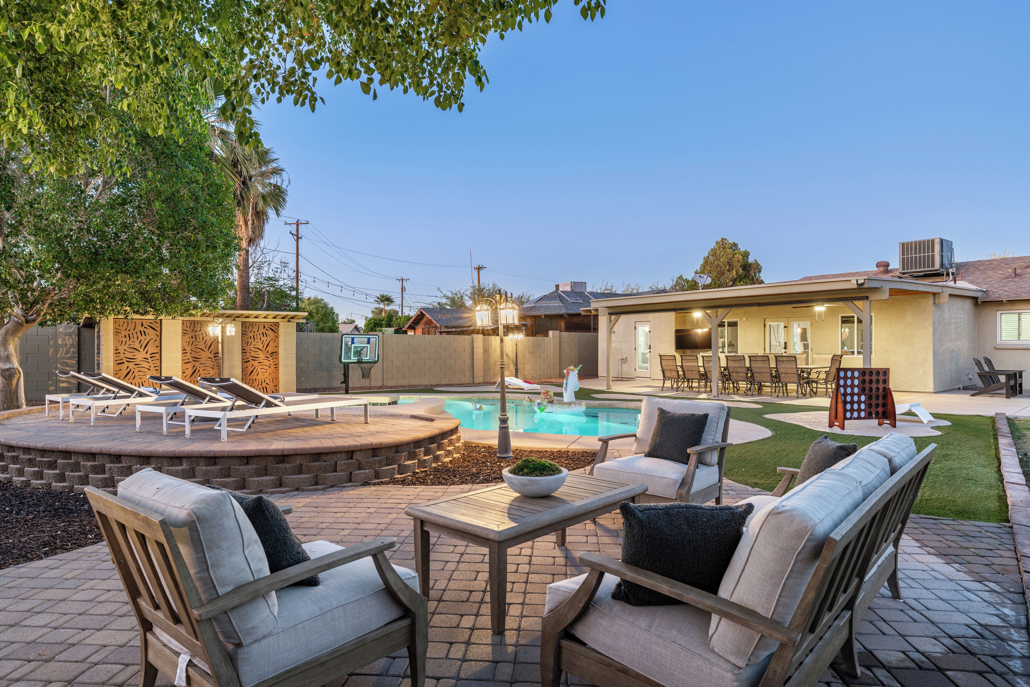 A backyard with a swimming pool, outdoor furniture, and a patio area.