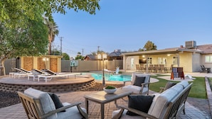 A backyard with a swimming pool, outdoor furniture, and a patio area.