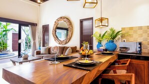 A dining area with a wooden table, chairs, and a buffet setup. - Villa Joyosa (Seminyak)