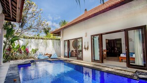 A modern pool area with a clear blue pool, a covered seating area, and a private room with a large sliding glass door. - Villa Joyosa (Seminyak)