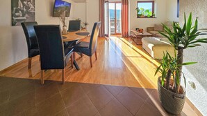 Un salon moderne comprenant un coin repas, un téléviseur à écran plat et une grande fenêtre avec des rideaux.