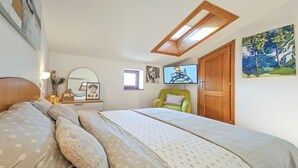 Une chambre à coucher avec un lit, une chaise, un bureau, un miroir et un tableau.