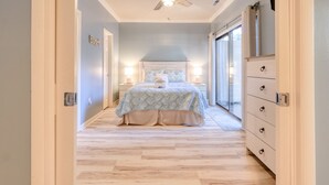 Une chambre à coucher avec un lit, des lampes de chevet, une commode et une vue sur l’extérieur, accessible par une porte coulissante.