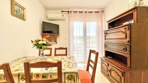 A dining area with a table set for four, a wooden cabinet, and a television on the wall.