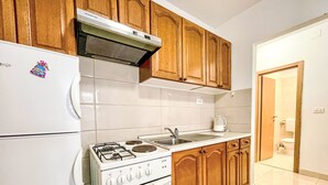 A kitchen with wooden cabinets, a white stove, and a sink.