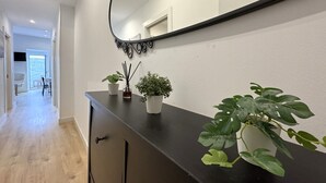 Ein Flur mit einer schwarzen Theke, zwei Topfpflanzen, einem Spiegel und einer Tür, die auf einen Balkon führt.