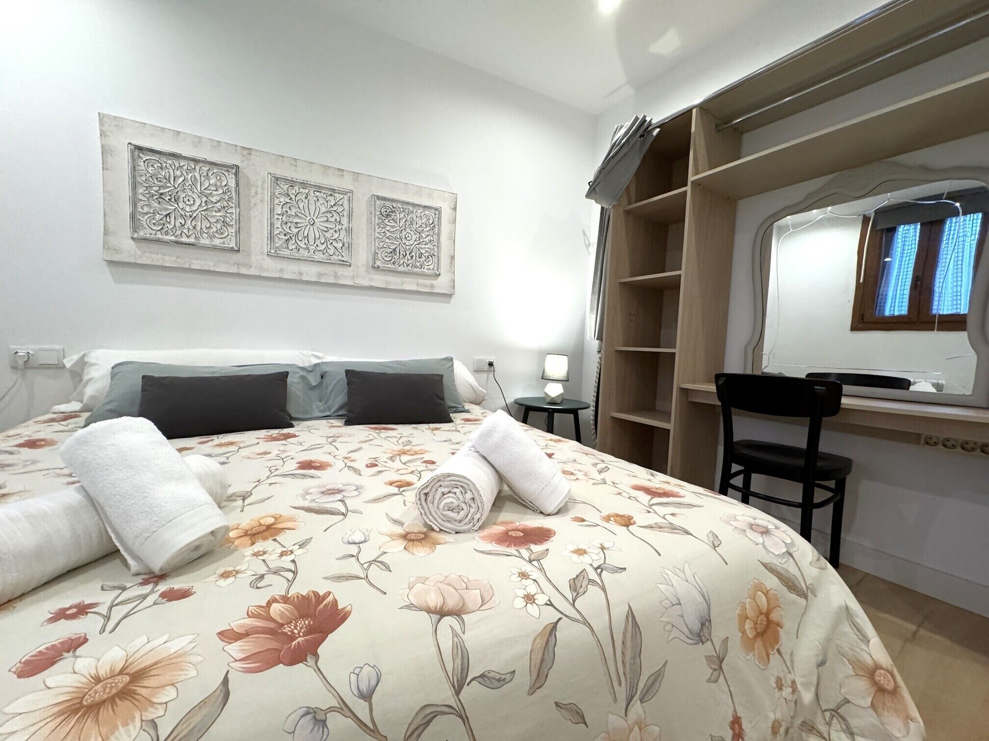 A hotel room with a bed, a desk, a chair, and a window.