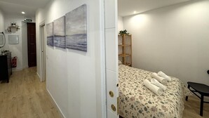 Ein Schlafzimmer mit einem Bett, einer Holzablage und einer Tür zu einem Flur.