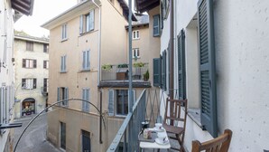 A narrow street with buildings on either side, a balcony with a table and chairs, and a cobblestone street. - Vicolo Ninguarda by Interhome (Valtellina)
