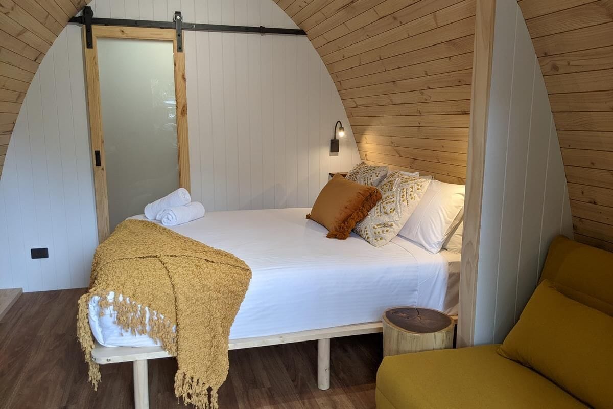 Un dormitorio acogedor con una cama, un banco y una pequeña mesa.