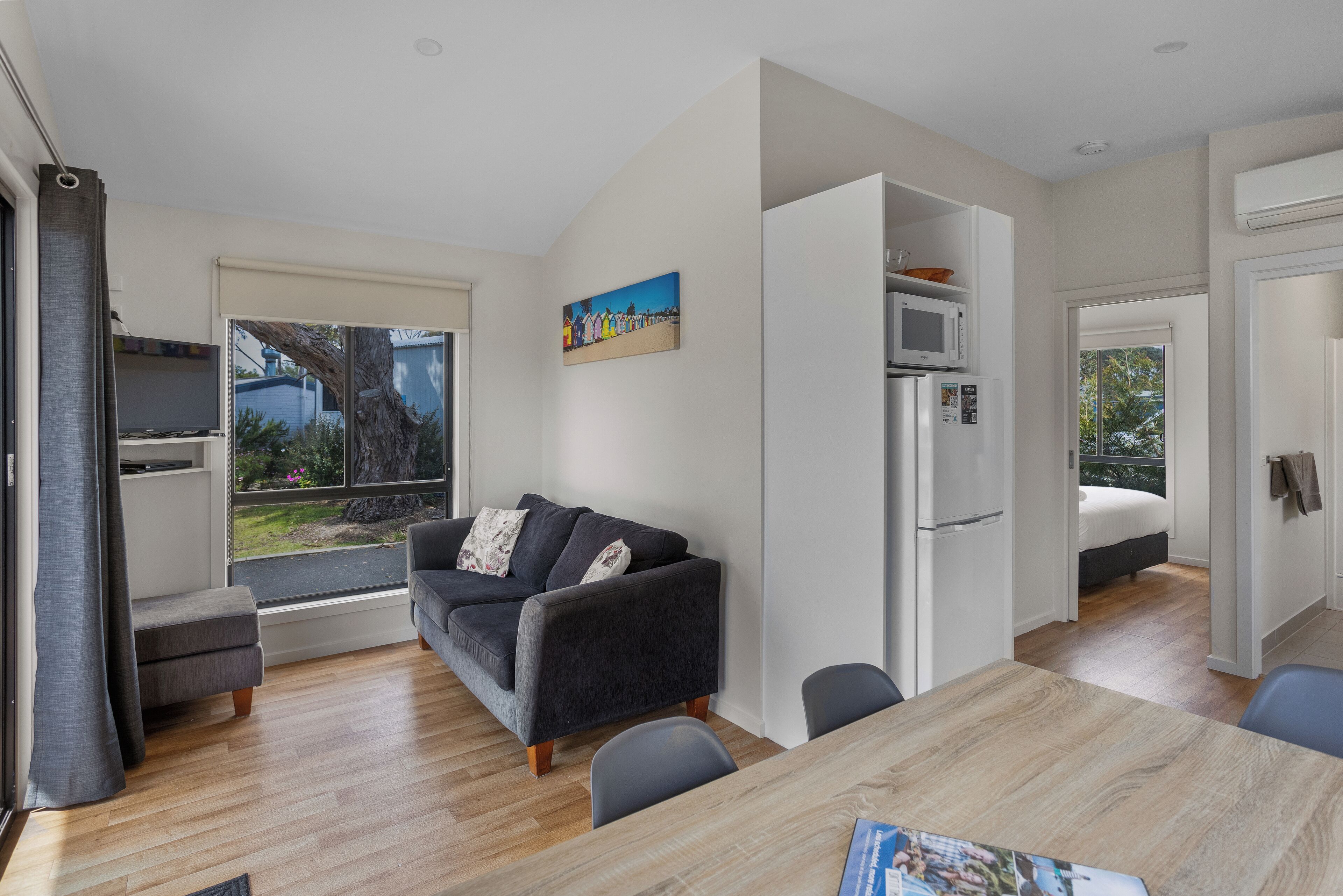 A modern living room with a sofa, a dining table, and a kitchen area.