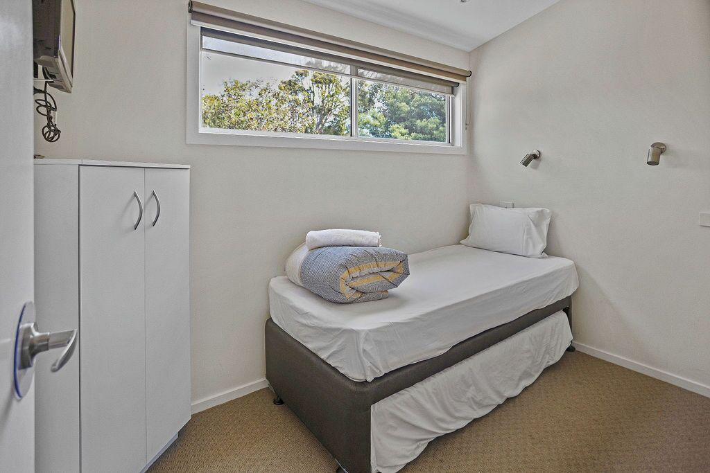 Un dormitorio con cama, armario, ventana y ventilador de techo.