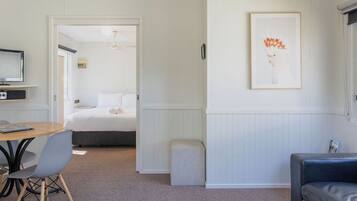 A modern room with a bed, a small table with chairs, a sofa, and a framed picture on the wall.