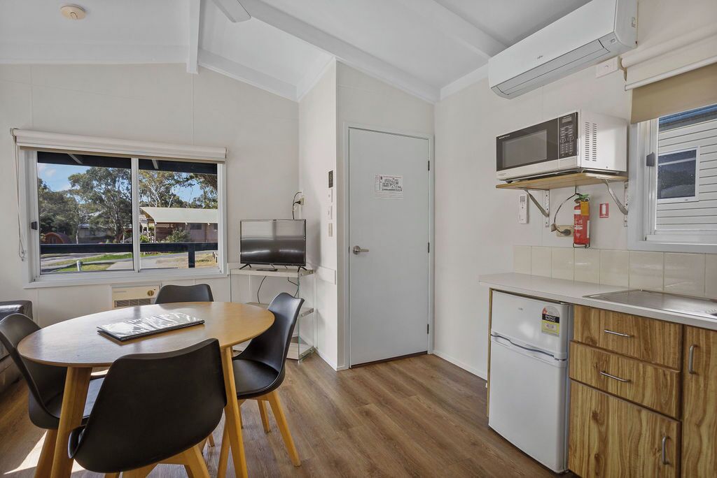 A compact kitchen with a dining area, a microwave, a small refrigerator, and a door with a sign.