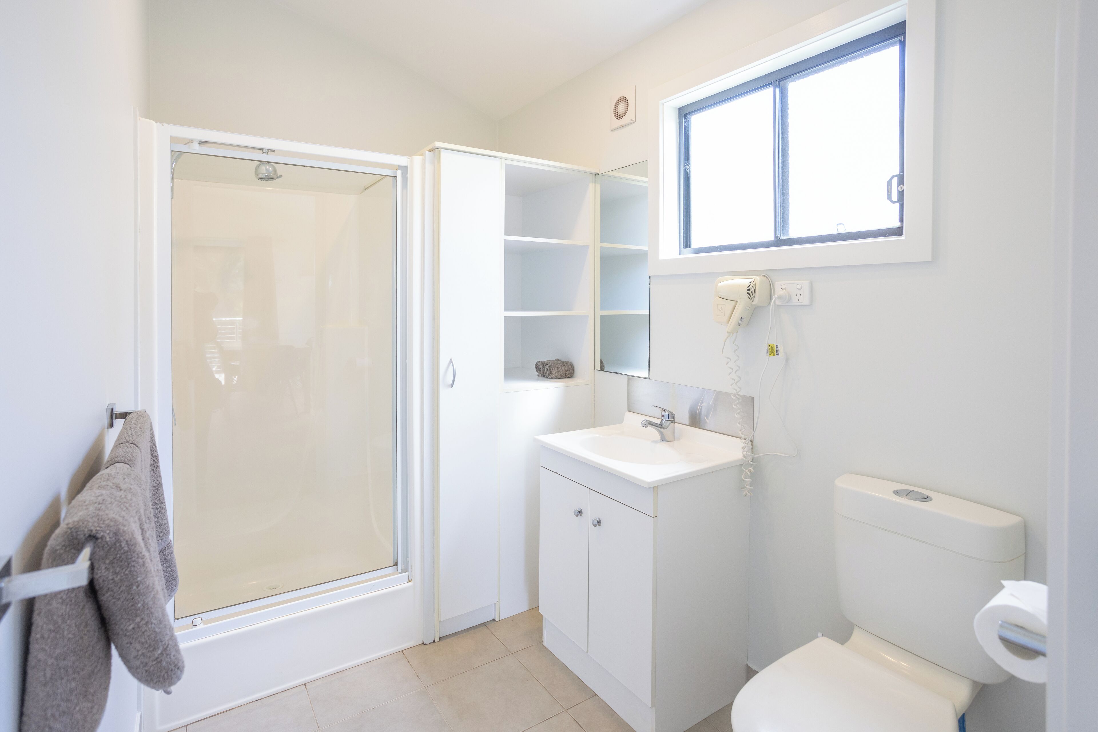 Une salle de bain avec douche, toilettes et lavabo.