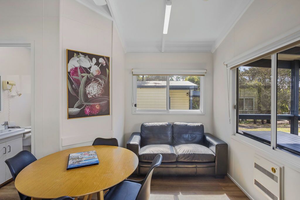 Una sala de estar moderna con una mesa de comedor de madera, un sofá de cuero y un amplio ventanal con vistas al exterior.