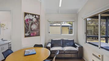 Una sala de estar moderna con una mesa de comedor de madera, un sofá de cuero y un amplio ventanal con vistas al exterior.